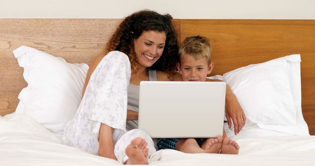 Smiling Mother and Son Using Laptop in Bed - Download Free Stock Images Pikwizard.com