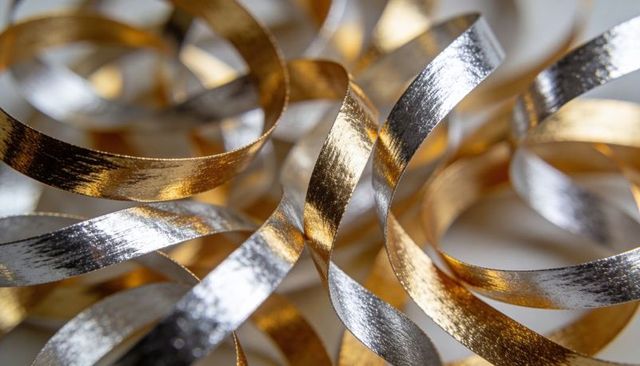 Shimmering gold and silver metallic curling ribbons close-up decorative abstract background