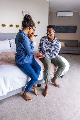 Surprise bedroom proposal romantic moment african american man presenting ring to partner