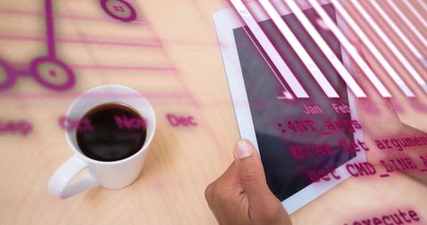 Hands tapping tablet touchscreen with coffee and pink code overlay, modern workspace