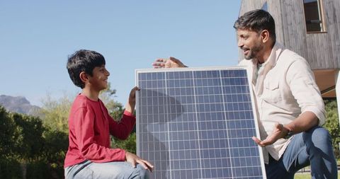 Father and Son Engaging with Solar Panel Outdoors