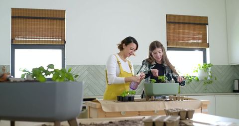 Friends planting seedlings on kitchen island for indoor gardening and sustainable living