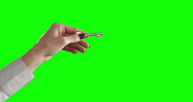 Close-up of a hand holding a metal key, set against a green screen background. Ideal for visual effects, security concepts, access metaphor, technology images, and innovation themes. Useful in promotional materials for security services or software tutorials.