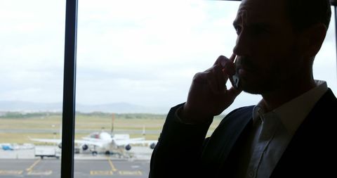 Businessman on phone at airport with plane in background
