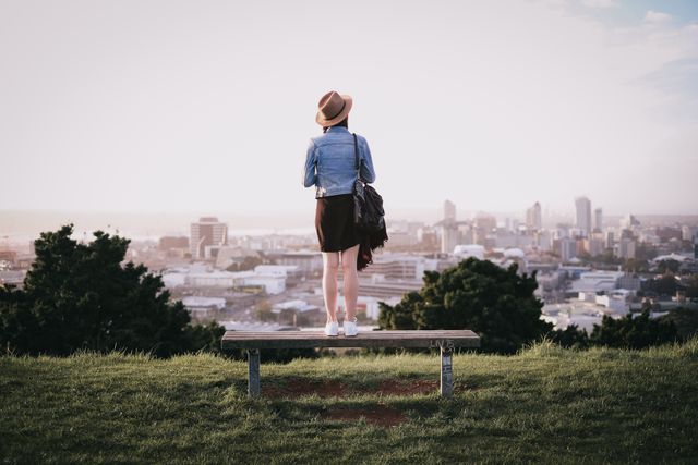 Young Woman Enjoying Cityscape from Hilltop Bench - Download Free Stock Photos Pikwizard.com
