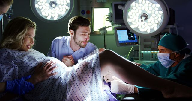 A Caucasian woman in labor is supported by a Caucasian man, the father, as a healthcare professional assists with the delivery, with copy space. Capturing a pivotal moment, the image conveys the intensity and support experienced during childbirth.