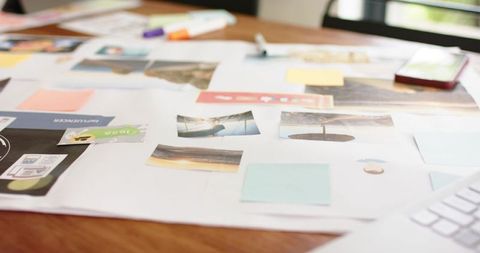Creative moodboard spread on wooden desk with prints sticky notes markers smartphone