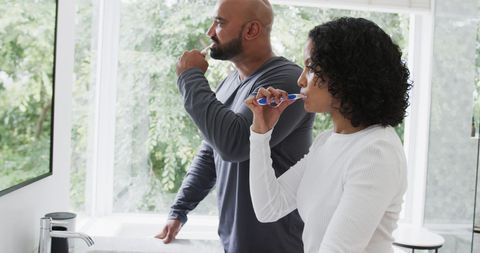 Morning Routine: Couple Brushing Teeth in Sunlit Bathroom