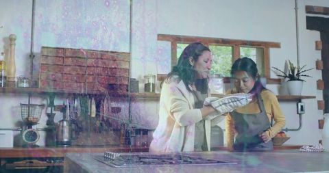 Mother teaching daughter baking in rustic modern kitchen with wooden shelves, oven mitts