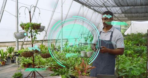 Greenhouse worker using handheld tablet for smart plant monitoring and propagation