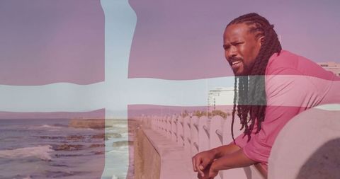 Contemplative man in pink shirt overlooking ocean on scenic promenade