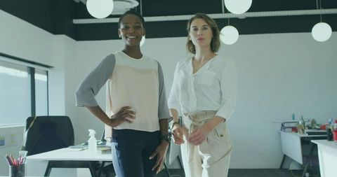 Professional Women Standing in Modern Office with Desks and Globe Lights