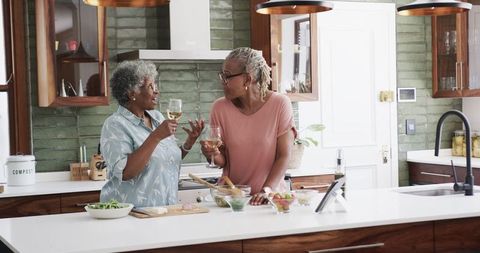 Senior Female Friends Cooking and Enjoying Wine at Home