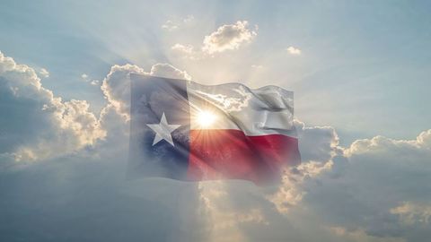 Texas Flag Floating in Radiant Cloudy Sky