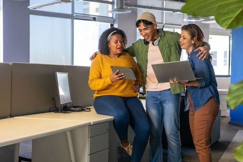 Multicultural team collaborating around tablet in bright open-plan office, teamwork