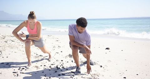 Athletic Couple Prepares for Beach Sprint Exercise on Sunny Shoreline
