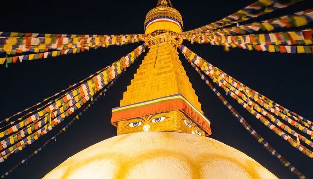 Boudhanath stupa night view glowing dome harmika eyes gilded spire prayer flags