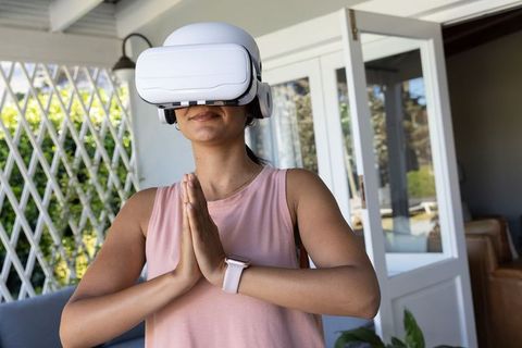 Practicing vr yoga on patio wearing white headset and smartwatch, home wellness lifestyle