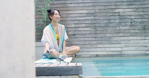 Woman Relaxing at Poolside in Resort Setting