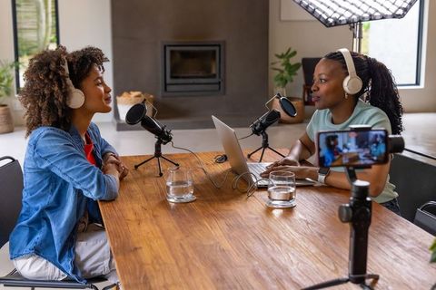African american women recording home podcast duo with professional microphones and laptop