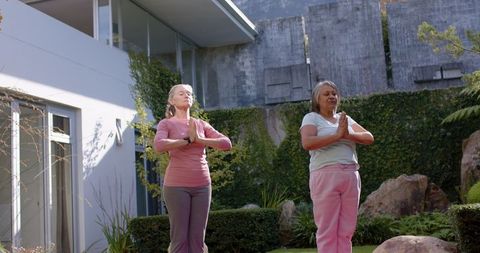 Multiracial Women Meditating Outdoors with Modern House Background