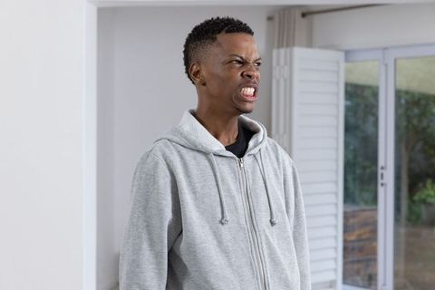 Man grimacing indoors in modern casual wear