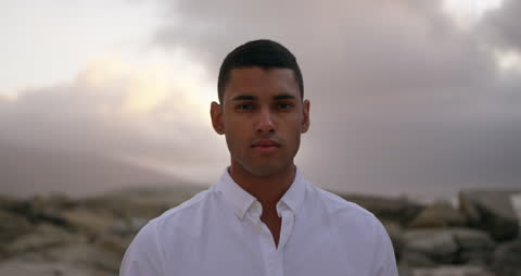 Young Man Standing on Beach at Dusk with Serene Expression