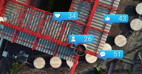 Aerial industrial gantry spanning storage tanks with social media notification overlays