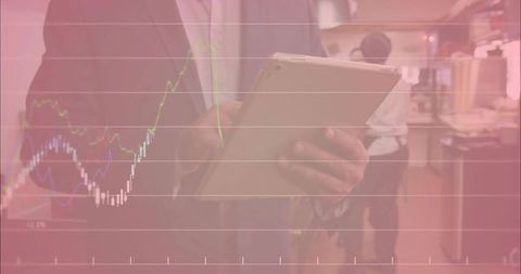 Corporate professional holding tablet reviewing candlestick financial charts in breakroom