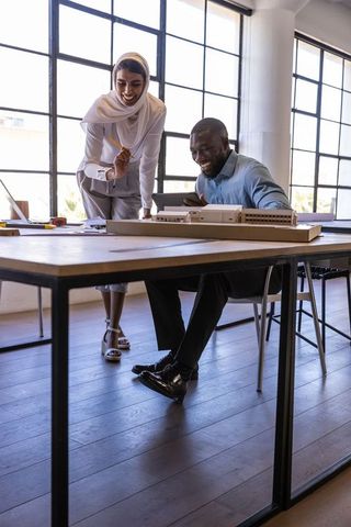 Diverse colleagues discussing scale model in architecture studio