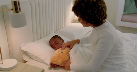Loving Mother Tucking Child Into Cosy Bedtime