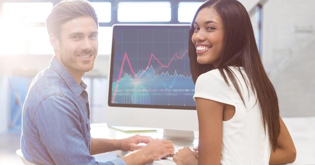 This image depicts two happy colleagues, a man and a woman, analyzing data on a desktop computer in a modern office. They are smiling and appear to be collaborating effectively. The computer screen shows graphs and charts, indicating data analysis or business performance review. This image is ideal for use in business presentations, corporate websites, teamwork and collaboration articles, and office environment promotions.