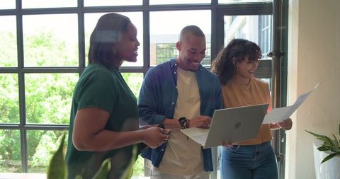 African colleagues collaborating by sunlit office window with laptop and documents