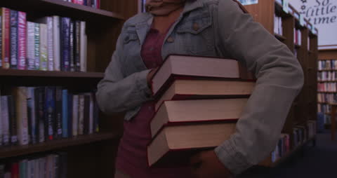 Female Student in Library Carrying Stack of Books