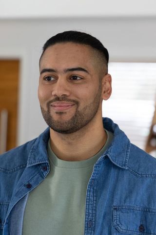 Smiling young man wearing denim shirt and green t-shirt looking left in home