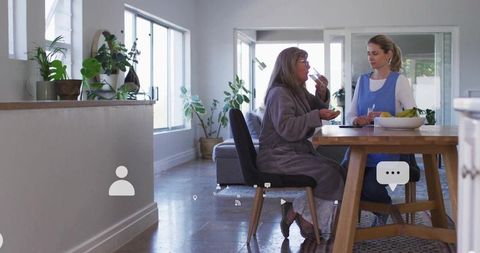 Elderly Woman Enjoying Yogurt With Caregiver in Cozy Home
