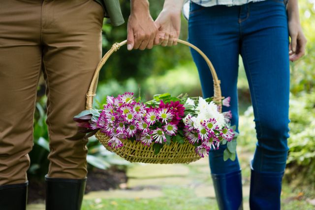 Mid-section of couple walking with flower basket in garden