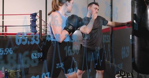 Female Boxer Training with Coach Guiding Punches in Boxing Gym with Data Overlay