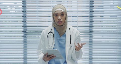 Confident Young Female Doctor with Tablet Wearing Hijab in Modern Clinic
