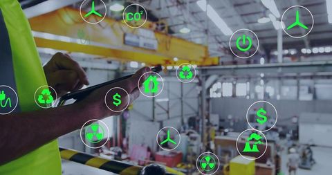 Industrial technician tapping tablet while monitoring augmented reality energy and safety icons