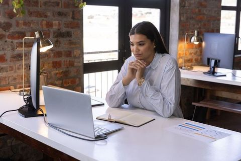 Professional businesswoman analyzing data on laptop in modern office