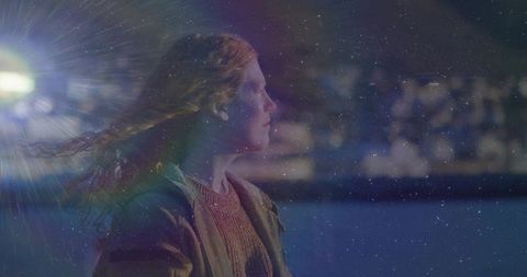 Contemplative woman under city lights at dusk