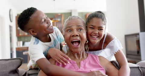 Joyful Grandchildren Hugging Excited Grandmother at Home