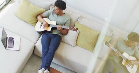 Young African American Man Playing Guitar Relaxing on Sofa - Download Free Stock Images Pikwizard.com