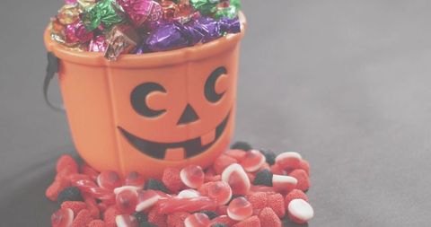 Jack-o'-lantern bucket overflowing with wrapped chocolates and assorted red gummies