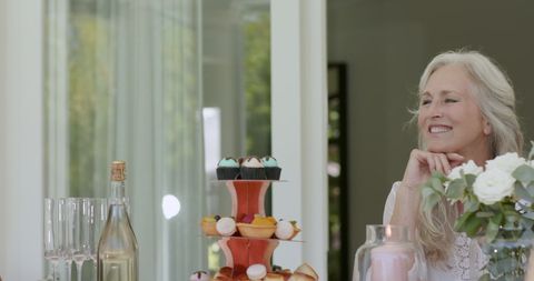 Joyful woman at celebration with cupcakes and champagne