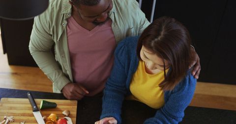 Diverse couple cooking together using tablet recipe in kitchen