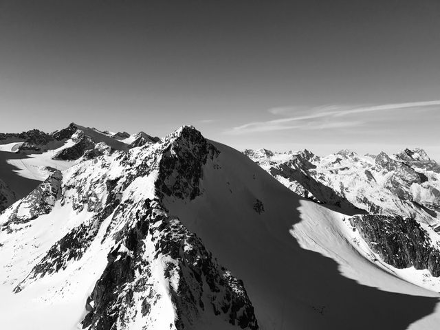 Shadows of mountain peaks create dramatic contrast in this black and white portrayal of a snow-covered mountain range. Useful for travel blogs, outdoor adventure advertisements, nature documentaries, winter sports promotions, and office decor.