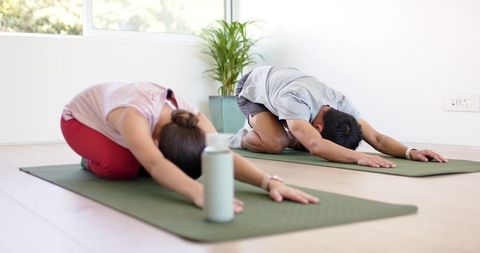 Asian man and african american woman practicing yoga and stretching in bright studio