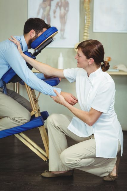 Physiotherapist giving arm massage to patient in clinic. Ideal for use in healthcare, wellness, and rehabilitation contexts. Can be used in articles, brochures, and websites related to physical therapy, pain relief, and medical treatments.
